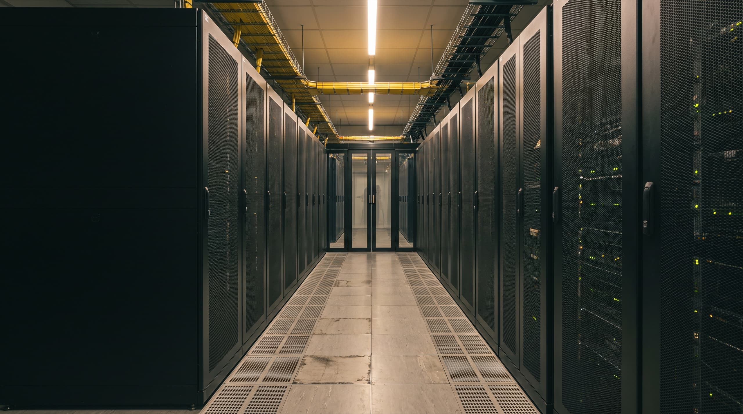 A long aisle of server racks under warm lighting in a modern data hall
